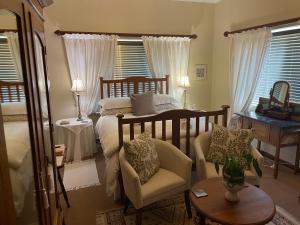a bedroom with a bed and a chair and a table at Ou Klipskuur Self-Catering Accommodation in Fraserburg