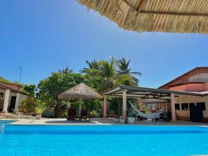 a resort with a swimming pool and a umbrella and chairs at Pousada Casa Eco Paracuru in Paracuru