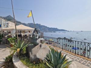 a statue sitting on a rock next to the water at ondina house in Giardini Naxos