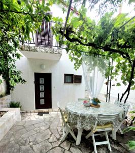 a patio with a table and chairs in front of a house at Buble Summer House in Rab