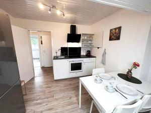 uma cozinha branca com uma mesa e cadeiras brancas em # VAZ Apartments WU12 Küche, TV, WLAN, Parkplatz, Autobahnähe em Schwelm