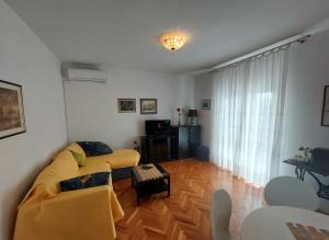 a living room with a yellow couch and a wooden floor at Buble Summer House in Rab