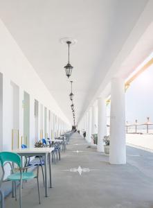 un long couloir avec des tables et des chaises dans un bâtiment dans l'établissement Hostel Cazino Nord Rooms, à Mamaia