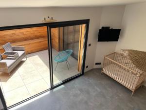 Zimmer mit Glastür, Stuhl und Kinderbett in der Unterkunft Le Corail in Mèze