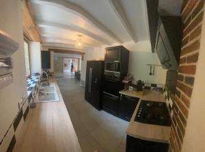 eine Küche mit schwarzen Schränken und einer Arbeitsplatte in der Unterkunft Les Loisons in Beauvoir