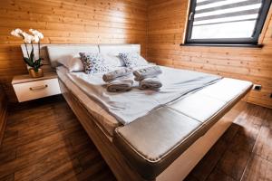 PodiazyOsada Skoczkowo komfortowe domki z jacuzzi nad jeziorem- sauna- balia- prywatny staw wędkarski的木墙和窗户的客房内的一张床位
