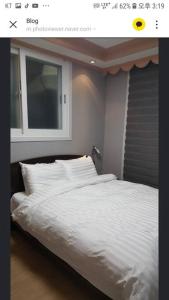 a bedroom with a white bed with a window at Private Mosageum in Yeosu