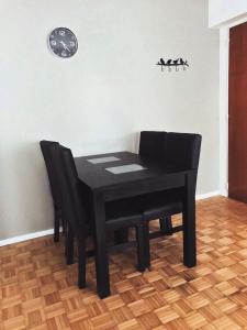 uma mesa preta com duas cadeiras e um relógio na parede em EC Apartments em Buenos Aires