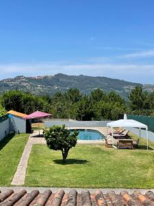 um jardim com uma piscina, uma mesa e uma árvore em Refúgio da Légua em Marco de Canavezes