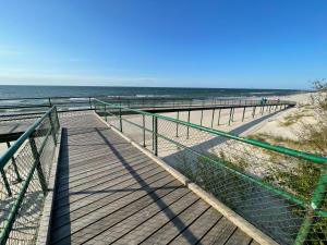 a boardwalk to the beach with the ocean in the background at Plażowa Park Apartment with Garden by Noclegi Renters in Międzywodzie +25 photos