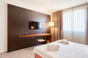 a hotel room with a bed and a tv on a wall at Hotel Cyrano in Saronno