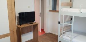 a room with a television on a desk with a bunk bed at Kuća Pećine in Metajna