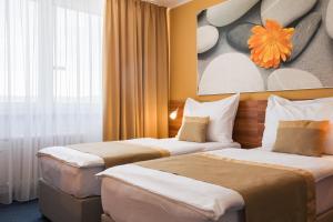 ブルノにあるホテル ビスタのベッド2台が備わる客室で、壁には絵画が飾られています。