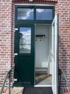 una puerta verde que conduce a un edificio de ladrillo en Skolan i Näsby lägenhet B, en Lövestad