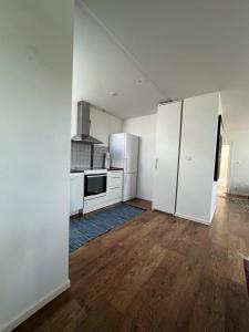 una cocina vacía con electrodomésticos blancos y suelo de madera en Skolan i Näsby lägenhet B en Lövestad