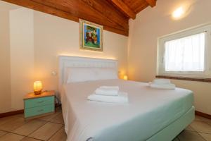 a bedroom with a large white bed and a window at Bertoletta Village Apartments in Peschiera del Garda +132 photos