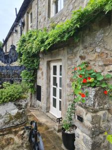 una casa de piedra con una puerta blanca y flores rojas en Home from home in Linton, en Linton