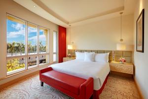 a bedroom with a large bed and a red bench at ITC Maratha, a Luxury Collection Hotel, Mumbai in Mumbai