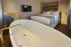 a bathroom with a bath tub next to a bed at Dolcemente Garni Hotel Superior in Izola