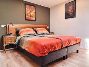 ein Schlafzimmer mit einem großen Bett mit orangefarbener Bettwäsche in der Unterkunft Vakantiestudio Huize Hout GR01 in Grijpskerke