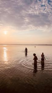 three people are standing in the water on the beach at Langhoff & Juul Boutique Hotel og Restaurant in Ebeltoft