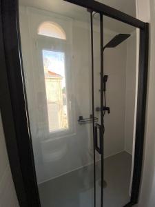 a bathroom with a glass shower with a window at Appartement, Royan. Proche plage. in Royan