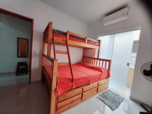 um quarto com 2 beliches e lençóis vermelhos em Apartamento Ubatuba Maranduba 150m da Praia em Ubatuba