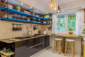 una cocina con estanterías azules y una barra con taburetes en Arthitekt I Afi Cotroceni, en Bucarest