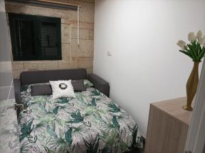 a bedroom with a bed with a green leafy comforter at Cabaña Refugio Barbanza in Boiro