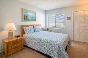 Un dormitorio con una cama y una lámpara y una ventana. en Oceanfront Condo with pool - Walk to the Tiki Bar, en Carolina Beach