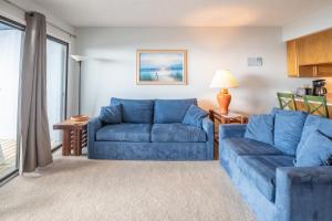 sala de estar con sofás azules y sofá en Oceanfront Condo with pool - Walk to the Tiki Bar, en Carolina Beach