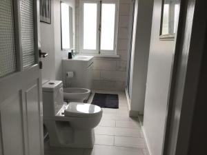 a white bathroom with a toilet and a window at Pousada da Vila in Vila Franca do Campo