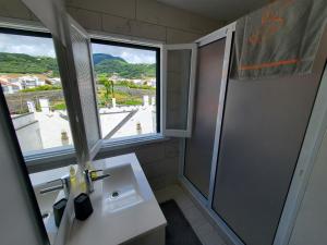 a bathroom with a sink and a window and a shower at Pousada da Vila in Vila Franca do Campo