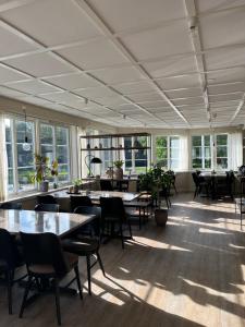 a large room with tables and chairs and windows at Tweed Hotell Skaftö in Fiskebäckskil