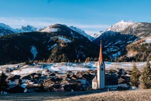 una iglesia en un pueblo con montañas cubiertas de nieve en Gasthof zur Post, en Sankt Lorenzen im Lesachtal