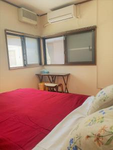 a bedroom with a red bed with a table and windows at Shonan no Oka no Villa - Vacation STAY 24987v in Fujisawa