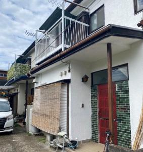 a white house with a red door and a balcony at Shonan no Oka no Villa - Vacation STAY 24987v in Fujisawa