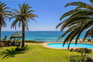 a swimming pool with palm trees and the ocean at Modern apartment, a home away from home 266 in Summerstrand