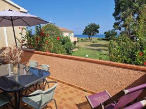 un patio con mesa, sillas y sombrilla en Pinea Mare, en Poggio-Mezzana