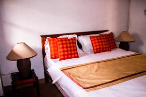 1 dormitorio con 1 cama con almohadas de color rojo y naranja en Villa Inavni, en Talawatugoda