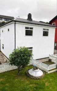 Una casa blanca con un árbol delante. en Cosy house near airport en Sørvágur