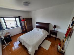 a bedroom with a bed with white sheets and a window at Pousada da Vila in Vila Franca do Campo
