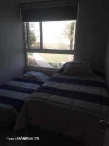 a bedroom with two beds in front of a window at Departamento en la playa en la laguna de cristal in Papudo