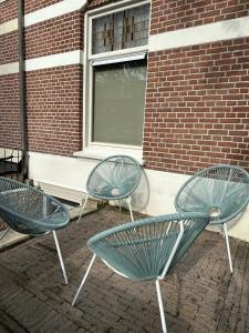 3 sedie verdi sedute di fronte a un edificio di Studio Senang a Nijmegen