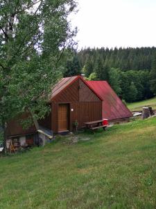 a barn with a red roof in a field at Apartmán Dvě Micky in Pec pod Sněžkou