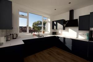 a kitchen with black cabinets and a large window at Beautiful large 3-bed coastal flat with parking. in Frinton-on-Sea