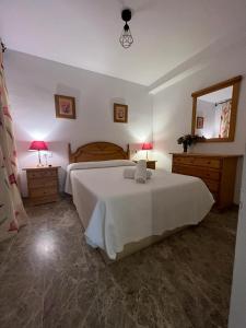a bedroom with a large white bed and a mirror at Apartamentos COZYNNS II in Torremolinos