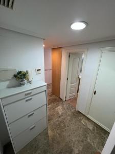 a kitchen with a white dresser and a hallway at Apartamentos COZYNNS II in Torremolinos