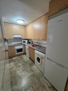 a kitchen with a white refrigerator and a dishwasher at Apartamentos COZYNNS II in Torremolinos