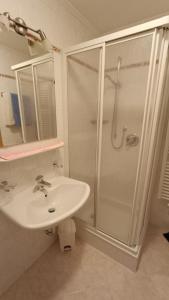 a white bathroom with a shower and a sink at Apartments Gana in La Villa